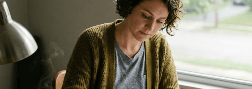 Woman writing in journal with a motivational quote by Arthur Ashe